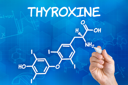Hand with pen drawing the chemical formula of thyroxine
